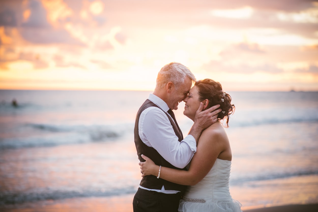 bride and groom hugging in front of the ocean