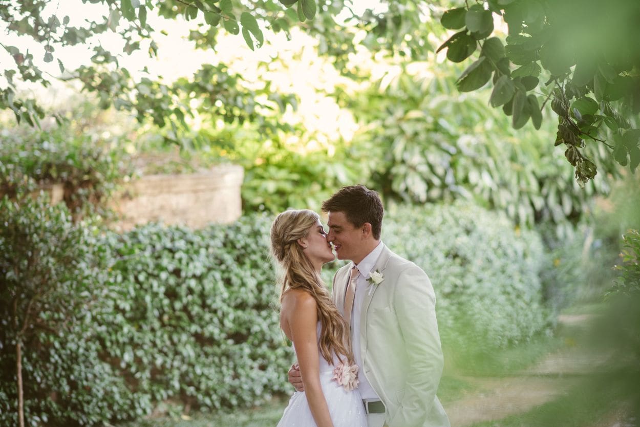 bride and groom holding each other outdoors surrounded by greenery